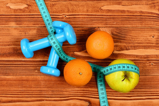 gym and health concept, dumbbells weight with measuring tape ,fruit