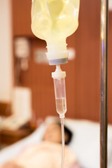 Closeup of saline bag in hospital room ,background blurred is patient on bed .