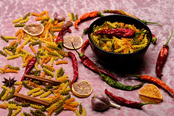 delicious colorful italian pasta, plate and ingredients on textured background