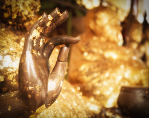 Closed up right hand of Buddha statue with gold sheet,selective focus and sunshine effect