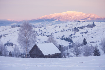 Fototapeta na wymiar Snowy mountain hills with wooden cabin