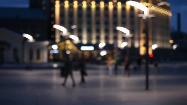 Out of focus background with blurry unfocused city lights and people walking at the square