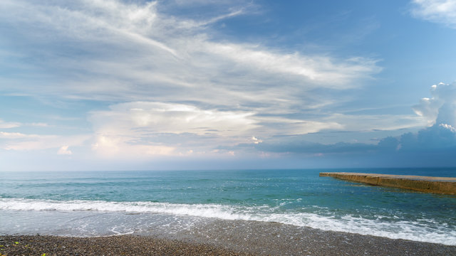 Fototapeta calm black sea pebble beach / turquoise water on the beach on the background of stratus clouds
