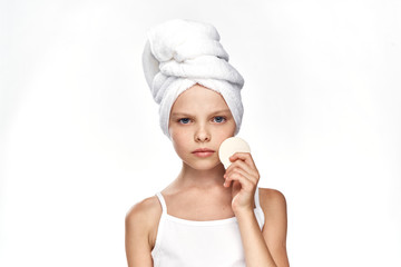 little girl in a towel keeps a makeup remover on a white isolated background