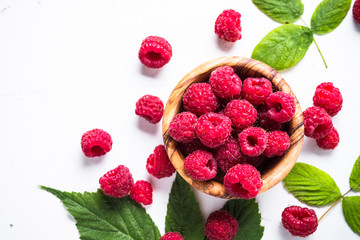Fresh raspberries in wooden bowl on white table. Top view.