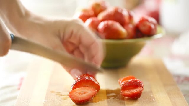 Female hands cutting fresh strawberry
