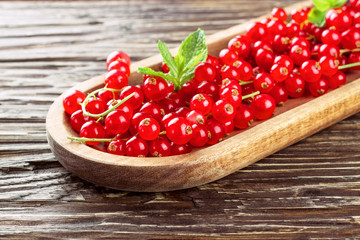 Ripe redcurrants in a wooden plate on a wooden background.