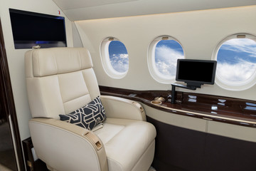 Comfortible cabin chair in the cabin of a modern business jet during flight.