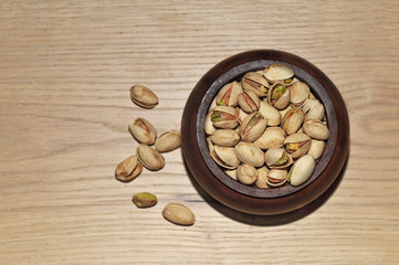 Pistachio nuts in little wooden bowl isolated