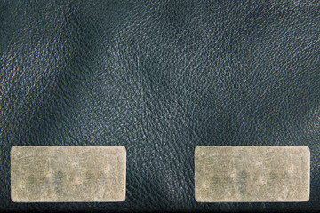 Texture of green leather jacket. Two metal labels for your text. The texture is a close-up macro shot.