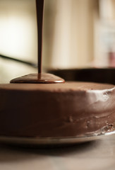 Chocolate ganache pouring over a frosted chocolate cake. Shallow depth of field.