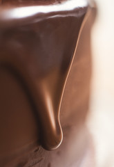 Chocolate ganache dripping down the side of a frosted chocolate cake.