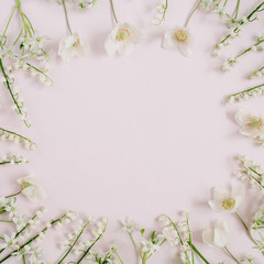 Frame of lily of the valley, green leaves with space for text on pink background. Flat lay, top view