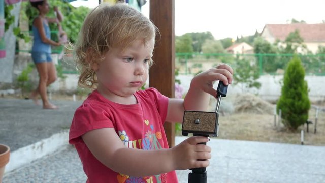 Baby playing with a monopod, kid is walking and exploring the monopod