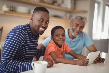 Fototapeta premium Happy multi-generation family using digital tablet in kitchen