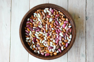 Pinto beans in bowl on wooden background. Different colors of dried pinto beans.