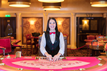 Cute lady casino dealer at poker table.