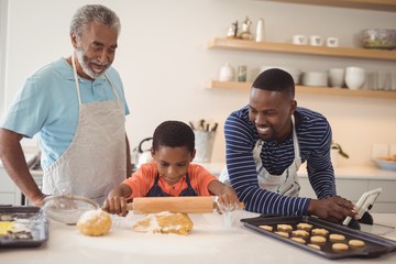 Fototapeta na wymiar Boy preparing cookie dough with his father and grandfather in