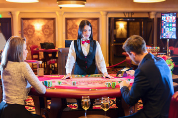 Cute lady casino dealer at poker table. Happy couple is playing Black Jack. © Yevgen Belich