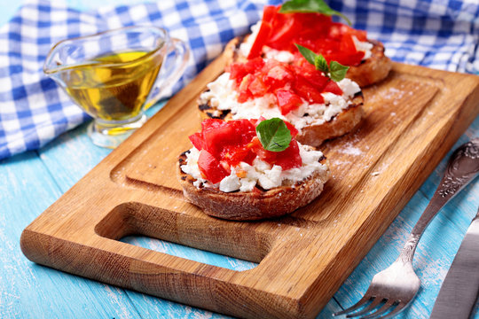 Delicious bruschetta with tomatoes, feta cheese,basil, dill and spice and olivia oil on wooden board.Selective focus