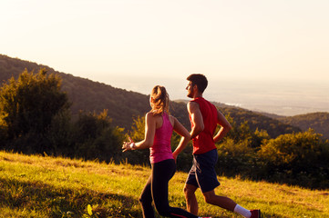 Young couple running in nature on sunset and having fun.