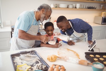 Multi-generation pouring milk in a jar while preparing cookies