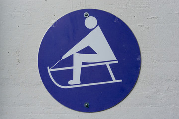 sled symbol on a blue plate with a white wall in the background