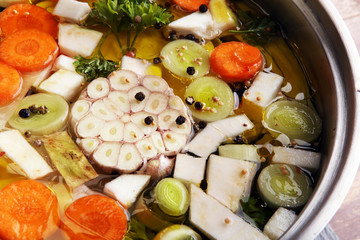 Broth with carrots, onions various fresh vegetables in a pot - colorful fresh clear spring soup. Rural kitchen scenery vegetarian bouillon or stock