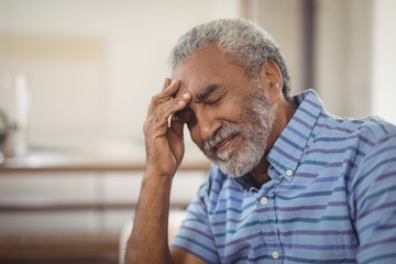 Tense senior man sitting in living room