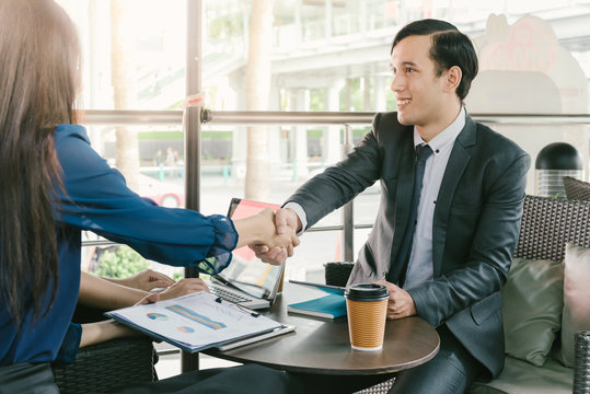Friendly smiling businessman and businesswoman handshaking over the coffee desk out side the office  after pleasant talk and effective negotiation, good relationships. Business concept photo