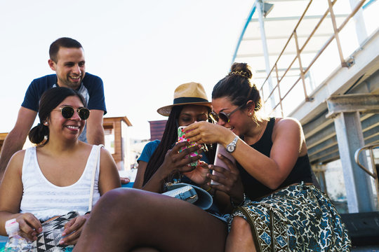 Friends with smart phones relaxing outside - Powered by Adobe