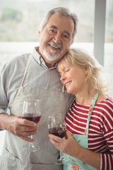 Smiling senior couple holding wine glass in kitchen