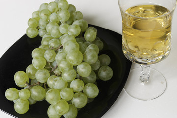 Wine and Grapes. Young White Wine and Green Grapes isolated on White Background