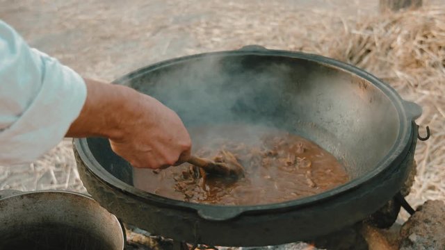 Close-up of the hand that stirs the soup with the spoon