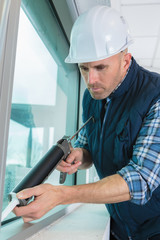 man in overall applying silicone sealant