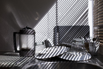 clean dishes in the kitchen. Beautiful light from the window blind. stripes