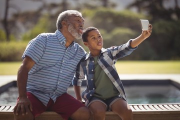 Grandson and grandfather taking selfie with mobile phone