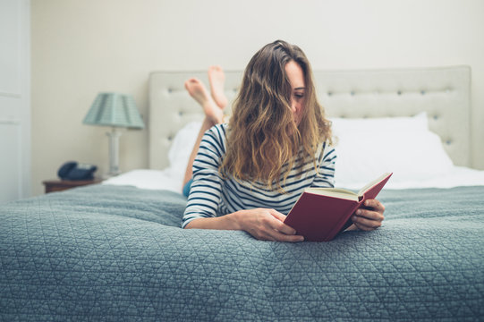Young woman reading book on bed