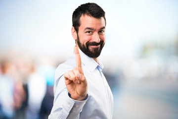 Handsome man with beard counting one on unfocused background