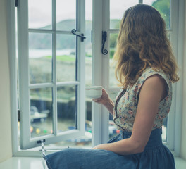 Young woman drinking tea by the window