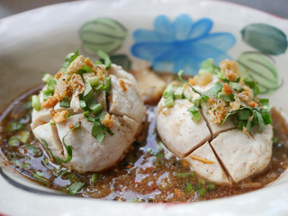 thai noddle of jumbo pork ball, pig liver, pork slide and vegetable on wooden table, hot noodle with blood pink for soup, in Thailand call Boat Noddle.