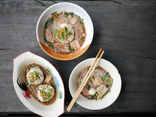 thai noddle of jumbo pork ball, pig liver, pork slide and vegetable on wooden table, hot noodle with blood pink for soup, in Thailand call Boat Noddle.