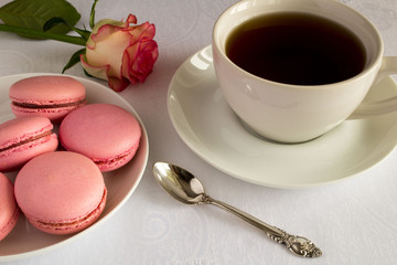 Breakfast with macaroons and tea on the white tablecloth