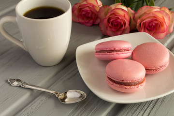 Pink macaroons and coffee on the grey wooden background