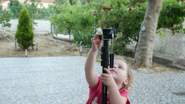 Kid playing with a monopod, child interested the monopod