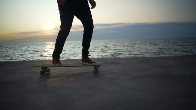 Hipster style boy in red shirt ride skateboard seaview sunrise rapid slow motion
