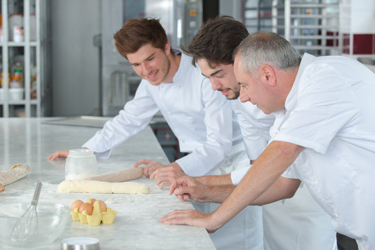 male chef decorating cake with whipped cream using piping technique