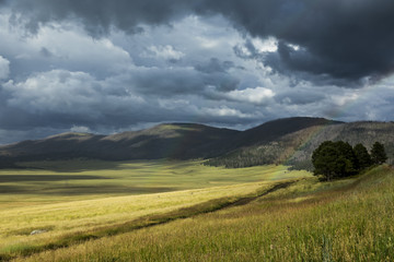 dark storm clouds, sun, and a double rainbow all in one beautiful caldera grassland