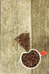 Coffee beans in a cup. Spilled coffee on a wooden table. Sales of fresh coffee.