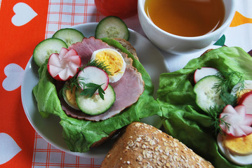 Polish sandwich breakfast with ham cucumber egg radish dill lettuce and hot tea